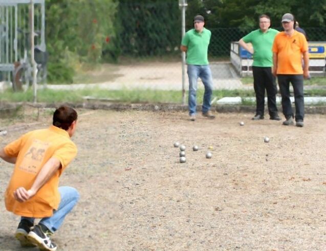 Ein Spieler wirft eine Kugel auf einen Bouleplatz, w&auml;hrend drei Beobachter zuschauen.