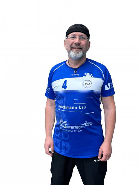 Mann in blauer Sporttrikots mit der Nummer 4, steht l&auml;chelnd vor einem wei&szlig;en Hintergrund.