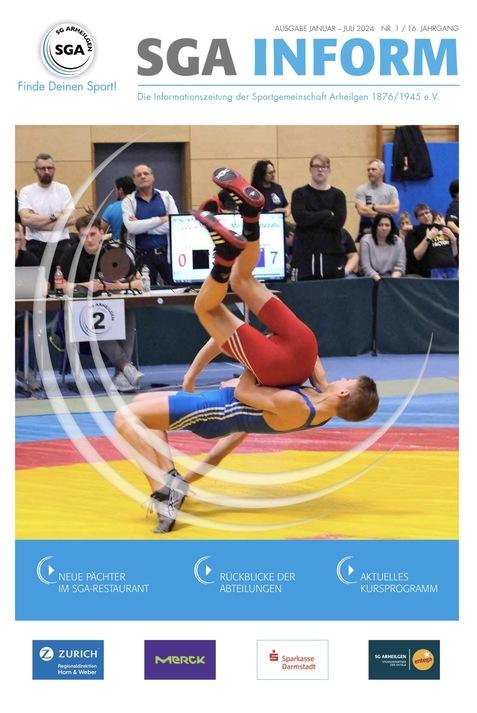 Zwei Ringer in Aktion während eines Wettkampfes auf einer bunten Matte in einer Sporthalle.