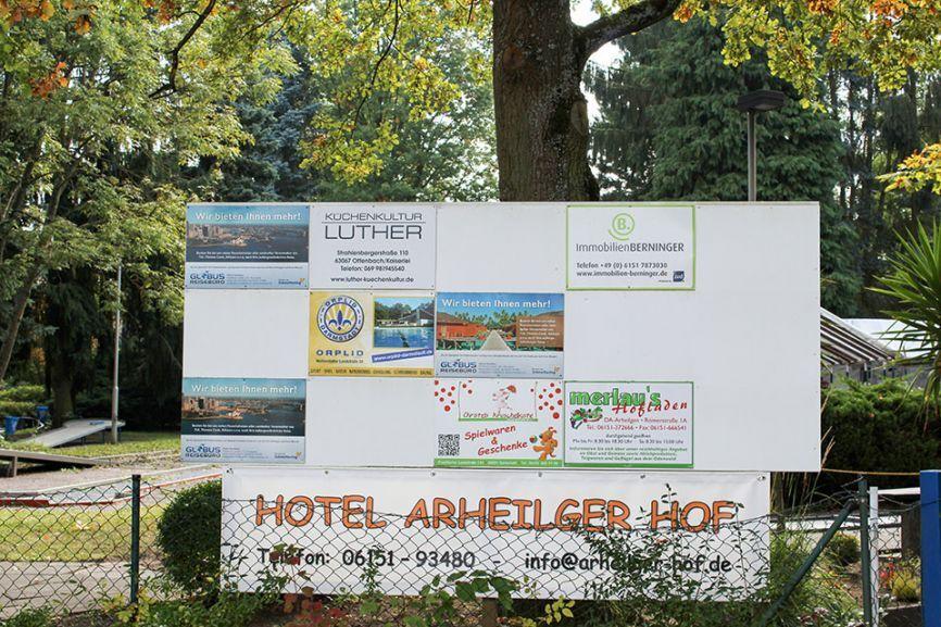 Informationstafel mit verschiedenen Plakaten und Werbung f&uuml;r Dienstleistungen, unter anderem Hotel Arheilger Hof.