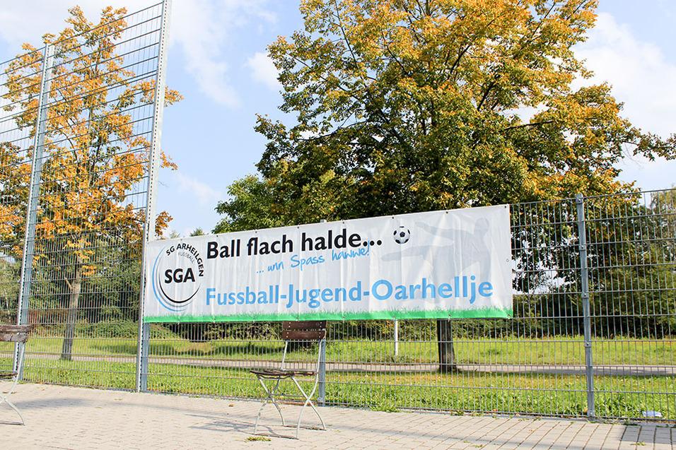 Banner für die Fußball-Jugend Oarhellje mit dem Slogan „Ball flach halten“ vor einem Sportplatz.
