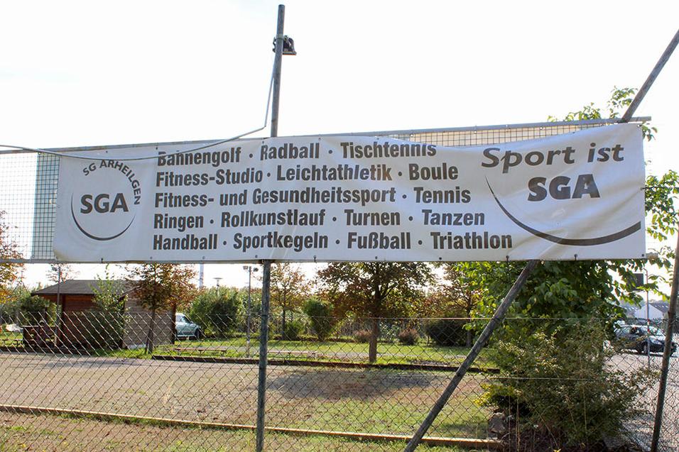 Banner mit der Aufschrift „Sport ist SGA“ und einer Liste von Sportarten, auf einem Zaun in einem Sportgelände.