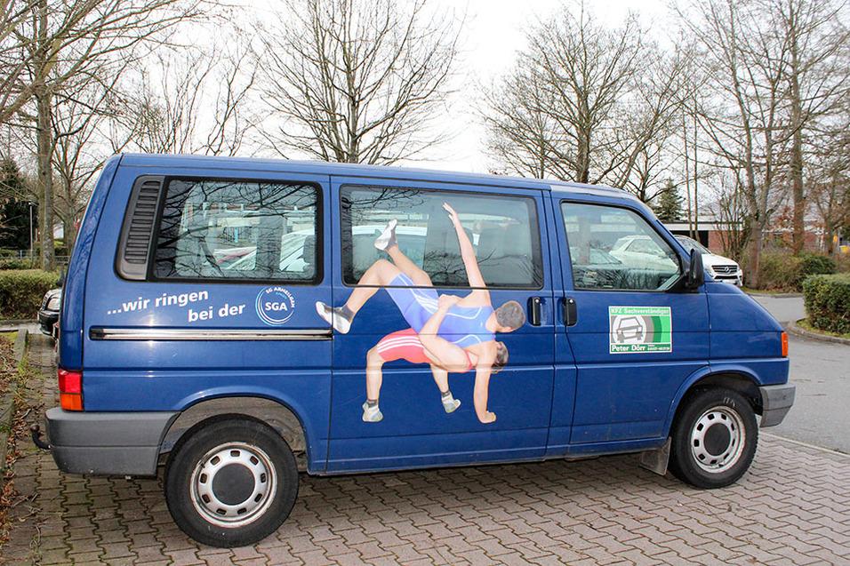 Blauer Transporter mit Werbung f&uuml;r Ringen, abgebildete Athleten zeigen eine Wettkampfszene auf der Fahrerseite.